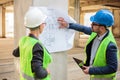 Two successful young architects looking at blueprints on a construction site Royalty Free Stock Photo