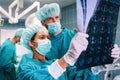 Team of surgeon doctors looking at x-ray film before surgery to set up diagnosis