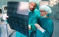 Team of surgeon doctors looking at x-ray film before surgery to set up diagnosis