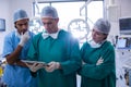 Team of surgeons discussing over digital tablet in operation room Royalty Free Stock Photo