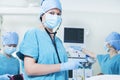 Team of surgeons in the operating room, female surgeon holding stethoscope and looking at camera