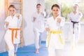 Team of teenage girls in kimonos stand in fighting stance during group karate training session