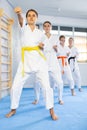 Team of teenage girls in kimonos stand in fighting stance during group karate training session