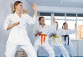 Team of teenage girls in kimonos uses new fighting techniques during karate lessons in gym