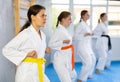 Team of teenage girls in kimonos uses new fighting techniques during karate lessons in gym