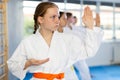 Team of teenage girls in kimonos uses new fighting techniques during karate lessons in gym