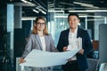 two architects working on house plan project, asian man and woman looking successful at camera and smiling Royalty Free Stock Photo