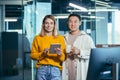 Team of two Asian male and female workers take a break, look at the camera and smile, use a tablet to discuss a joint business Royalty Free Stock Photo