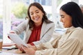 Team of two smiling business women using a digital tablet for a brainstorm meeting in the office. Happy confident ethnic Royalty Free Stock Photo