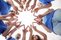 Team of volunteers putting their hands together on light background