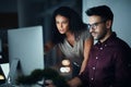 The team that wont stop until its done. two colleagues using a computer together during a late night at work.