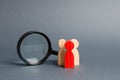 Team of wooden human figure stands near a magnifying glass on a gray background. The concept of the search for people and workers