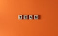 Team word phrase in wooden letters. Motivation and slogan. Orange background