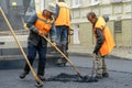 A team of workers with shovels is working on laying new asphalt. Road repairs. Workers with tools next to a roller asphalt stacker Royalty Free Stock Photo