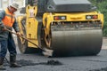 A team of workers with shovels is working on laying new asphalt. Road repairs. Workers with tools next to a roller asphalt stacker Royalty Free Stock Photo