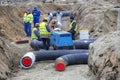 Team of workers in a trench installing district heating pipe