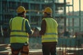 Team of workers wearing safety vests and helmets having a discussion at an active construction site Royalty Free Stock Photo