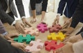 Team of young business people connecting colorful parts of jigsaw puzzle on table