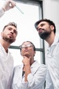 Team of young chemists examining test tube with reagent in lab