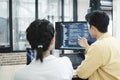 Team of young computer programmers cooperating while working on desktop PC in the office.