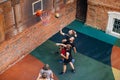 team of young guys playing basketball in the yard and throw the ball in the basket. Aerial view from