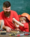 Teamwork and assistance concept. Father, parent with beard teaching little son to use tool screwdriver. Boy, child busy Royalty Free Stock Photo