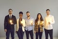 Diverse interracial business team with glowing lamp standing on grey copy space