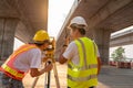 Teamwork of civil engineer and surveyor engineers use radio communication and making measuring with theodolite on road works. Royalty Free Stock Photo
