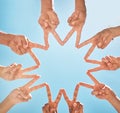 Teamwork, community and group support with fingers in a star shape from below against a blue sky background. A diverse