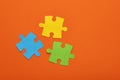 Teamwork concept - Three puzzle pieces of blue, green and yellow color on orange background Royalty Free Stock Photo