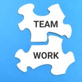 White jigsaw puzzles written TEAMWORK isolated on blue background. Royalty Free Stock Photo