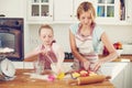 Teamwork ensures their bakings success. Cute little girl baking in the kitchen at home with her mom. Royalty Free Stock Photo