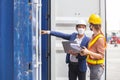 Teamwork foreman man and woman wearing protection face mask and safety helmet using laptop and holding clipboard checking containe Royalty Free Stock Photo