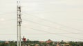 Teamwork of four workers in metal lighting pole with lift bucket during installation of lighting equipment in suburb area of