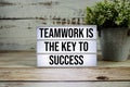 Teamwork is the Key to Success text on light box with alarm clock on wooden background Royalty Free Stock Photo