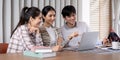 Teamwork and Learning. Three students collaborating on a project using a laptop in a bright and modern study space. Royalty Free Stock Photo