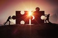 Teamwork, partnership and cooperation concept. Silhouettes of two businessman joining two pieces of puzzle together