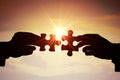 Teamwork, partnership and cooperation concept. Silhouettes of two hands joining two pieces of puzzle together Royalty Free Stock Photo