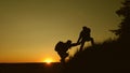 Teamwork silhouette of group of hikers lends a helping hand in climbing mountains, hill. Uristy climb mountain at sunset Royalty Free Stock Photo