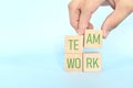 Teamwork and team building business concept. Hand putting together wooden blocks wood puzzle pieces in blue background. Royalty Free Stock Photo