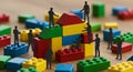 Teamwork: Tiny figures construct a building block tower, emphasizing collaboration and collaborative construction on a wooden Royalty Free Stock Photo