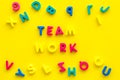 Teamwork training concept. Text teamwork lined with colored letters near toy letters on yellow background top view copy