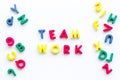 Teamwork training concept. Text teamwork lined with colored letters near toy letters on white background top view space