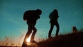 Teamwork. Two hikers enjoying sunrise walking from top of a mountain and dog. slow motion video. Two hikers with