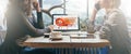 Teamwork, two young businesswomen sitting across table from each other. On table laptop, coffee cup and tablet computer. Royalty Free Stock Photo