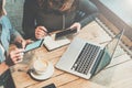 Teamwork. Two young businesswomen sitting at table in coffee shop, look at your smartphone screen and discuss business strategy.