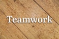 `Teamwork` white text on a wooden background.