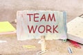 TEAMWORK word written on a piece of paper on an abstract background next to a calculator, paper clips and self-adhesive paper