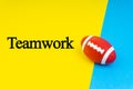 TEAMWORK words written and Rugby ball on blue and yellow background
