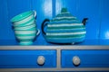 Teapot with blue and green knitted tea cosy and cups Royalty Free Stock Photo